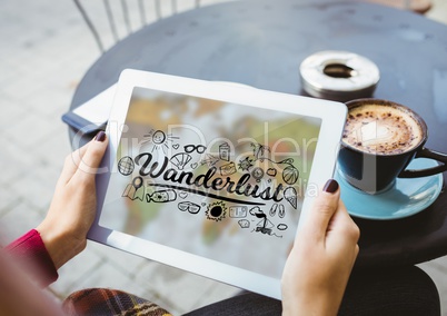 Woman at cafe holding tablet showing black wanderlust doodles against blurry map