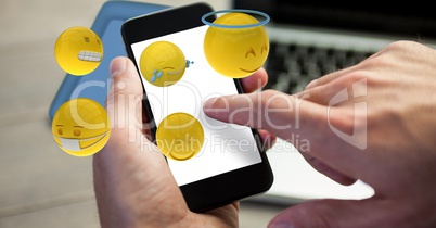 Close-up of hands using smart phone with various smiley faces