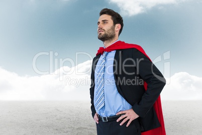 Businessman wearing cape while standing against sky