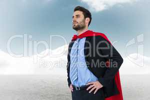 Businessman wearing cape while standing against sky