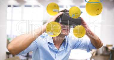 Digital composite image of businessman looking at emojis through VR glasses