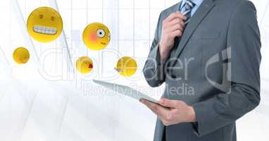 Business man mid section with tablet next to emojis and flare against white window