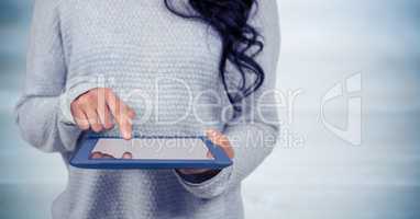 Woman mid section with tablet against blurry blue wood panel