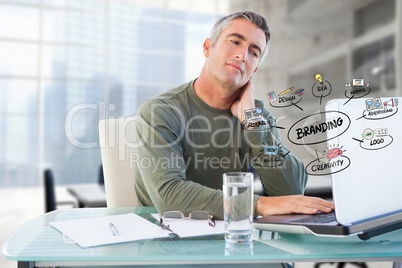 Businessman using laptop with colorful business branding doodles in office