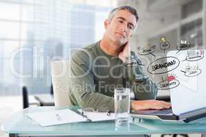 Businessman using laptop with colorful business branding doodles in office
