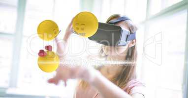 Digitally generated image of emojis flying over against woman using VR glasses at home
