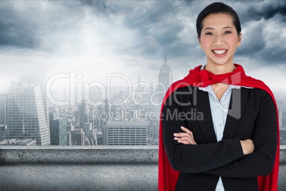 Portrait of businesswoman wearing cape while standing against city
