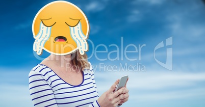 Woman with crying emoji on face texting on smart phone