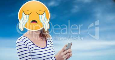 Woman with crying emoji on face texting on smart phone