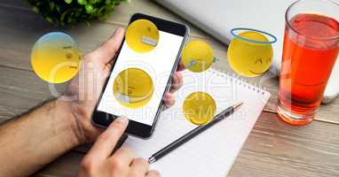 hand using smart phone while emojis flying over table