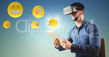 Man in VR using tablet with emojis and flare against blue green background