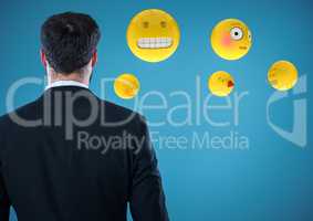 Back of business man with emojis against blue background