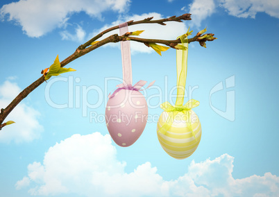 Easter eggs hanging on branch in front of blue sky