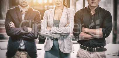 Confident businesspeople standing with arms crossed in office