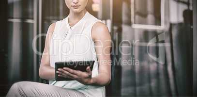 Businesswoman using digital tablet while sitting on chair