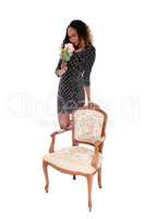 Young lady standing behind armchair.