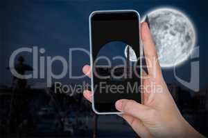 Composite image of human hand holding mobile phone against white background
