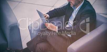 Businessman sitting on chair using digital tablet