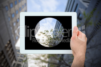 Composite image of hand holding tablet pc