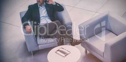 Businessman sitting on chair and talking on mobile phone