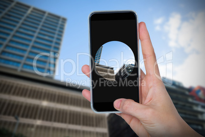 Composite image of human hand holding mobile phone against white background