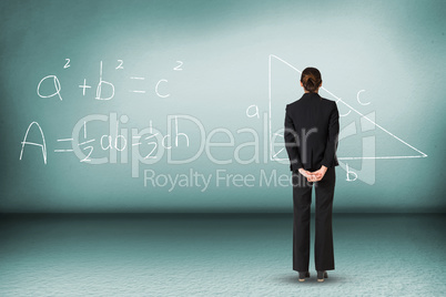 Composite image of businesswoman standing with hands behind back