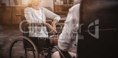 Businesswoman in wheelchair talking with colleague in office