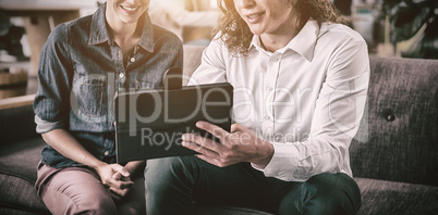 Smiling business colleagues discussing over digital tablet