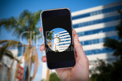 Composite image of hand holding mobile phone against white background