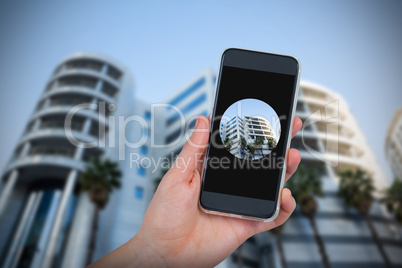 Composite image of hand holding mobile phone against white background