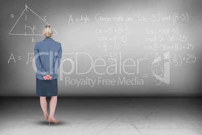 Composite image of businesswoman standing with hands behind back