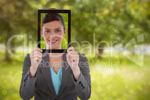 Composite image of businesswoman holding digital tablet