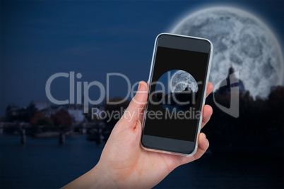 Composite image of hand holding mobile phone against white background