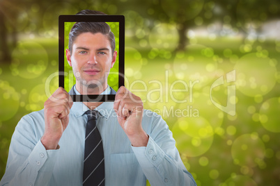 Composite image of businessman holding digital tablet in front of face