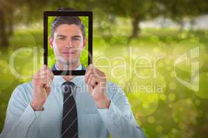 Composite image of businessman holding digital tablet in front of face