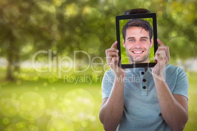 Composite image of man holding digital tablet in front of face