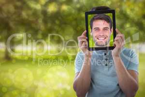 Composite image of man holding digital tablet in front of face