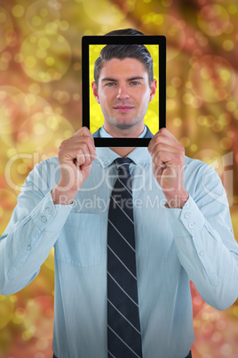 Composite image of businessman holding digital tablet in front of face