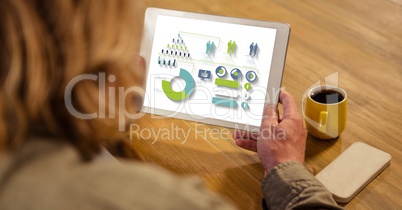 High angle view of businesswoman looking at graphs and chart in tablet computer while sitting by tab