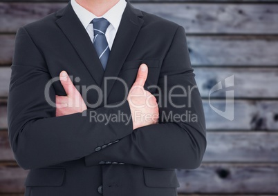Business man mid section with arms crossed against blurry blue wood panel
