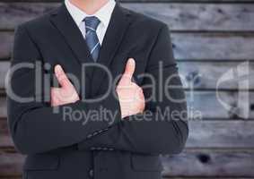 Business man mid section with arms crossed against blurry blue wood panel