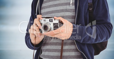 Man with camera mid section against blurry blue wood panel