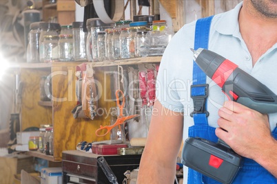 Midsection of carpenter holding drill at workplace