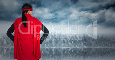 Back of business woman superhero with hands on hips against skyline