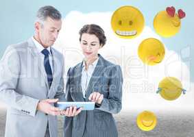 Business people with tablet against cloud and ground with emojis