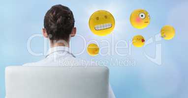Back of business woman in chair with emojis and flare against blue background