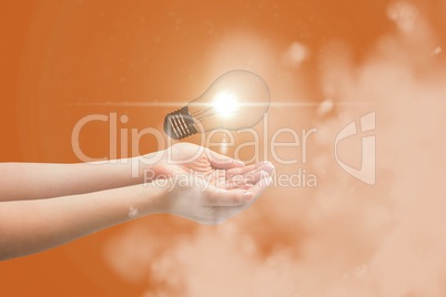 Digital composite image of light bulb over hands