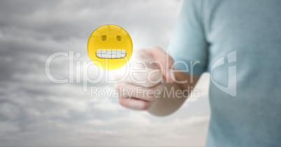 Man in tshirt pointing at emoji with flare against cloudy sky