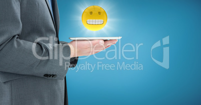 Business man mid section with tablet and emoji with flare against blue backround