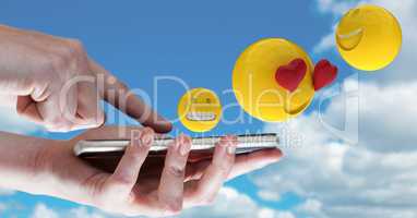 Digitally generated image of emojis flying over hands using smart phone against sky